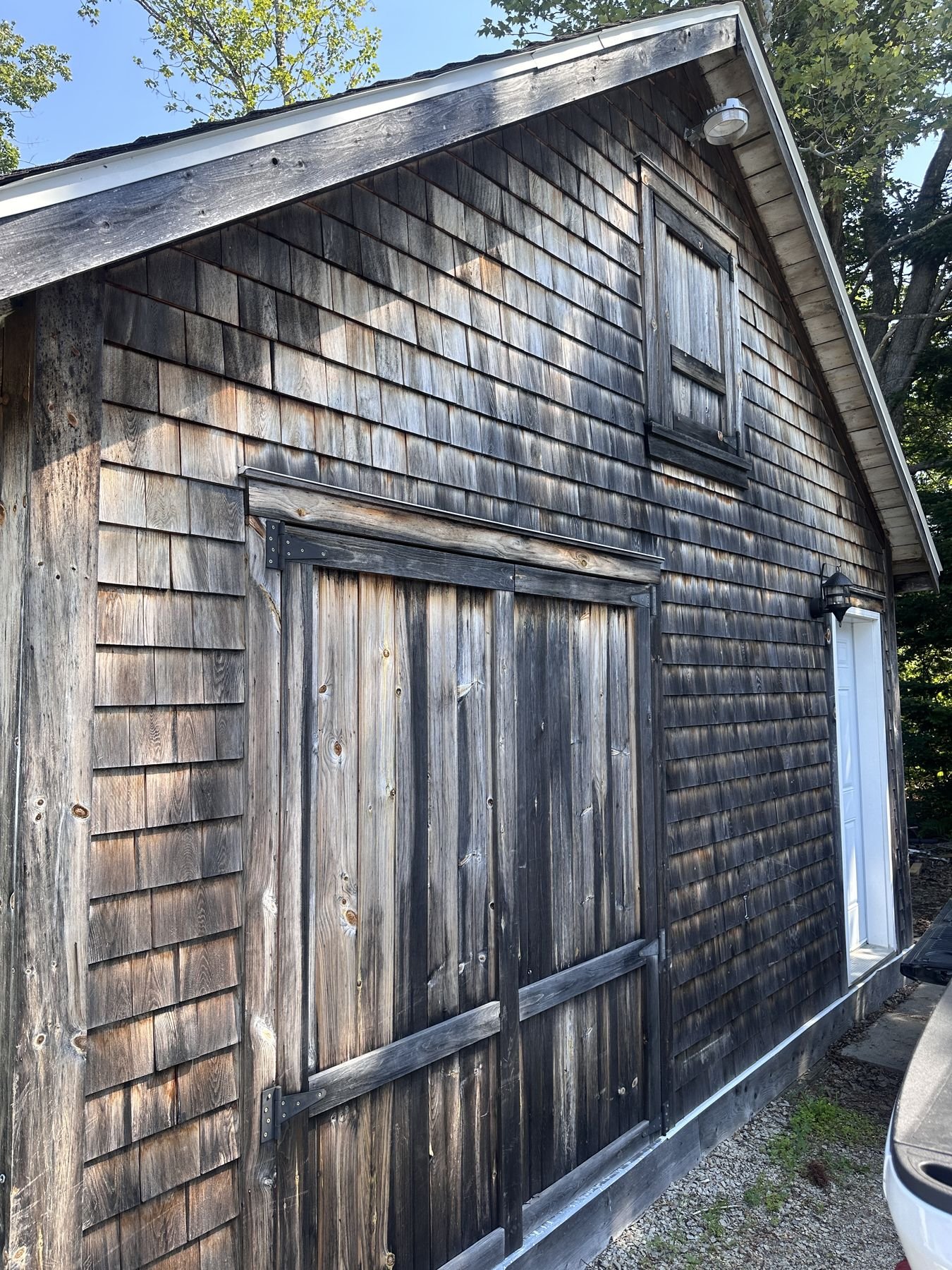 Weathered cedar shake roof on a shed with dark algae and lichen staining
