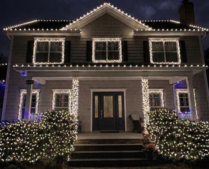 Warm-white holiday roofline lighting, wrapped columns and a lit wreath on a Halifax home